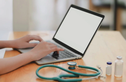 Laptop Near Teal Stethoscope In Wooden Table Free Stock Photo