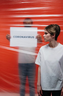 Woman With A Stressful Look At A Man Holding A Poster With Coronavirus Text Free Stock Photo