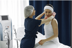 Woman in Blue Scrub Suit Helping Woman Sitting on Bed Free Stock Photo