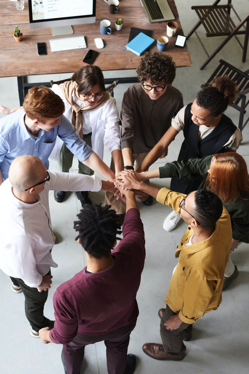 People of different ethenicities standing in a circle holding hands - Diversity.